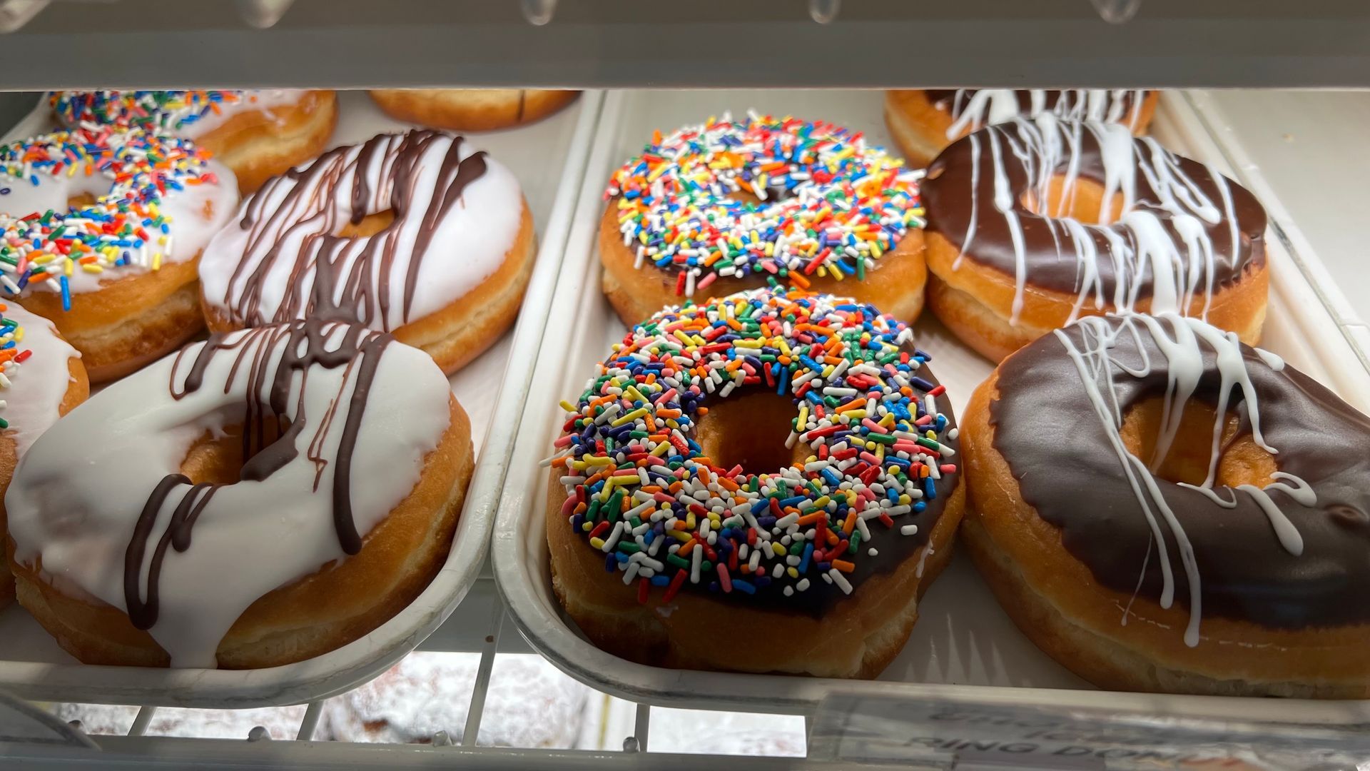 A tray of donuts with different toppings and sprinkles