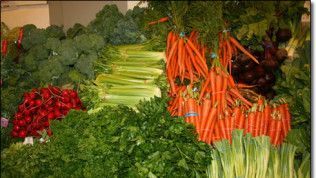A bunch of vegetables including carrots , celery , broccoli and radishes are sitting on a table.