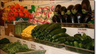 A variety of vegetables are displayed on a shelf in a grocery store.