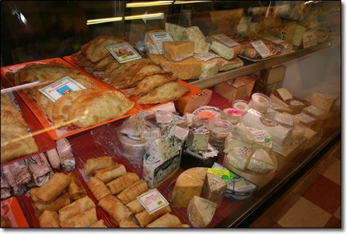 A display case filled with a variety of cheeses and pastries.