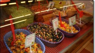 A display case filled with bowls of food and spoons.
