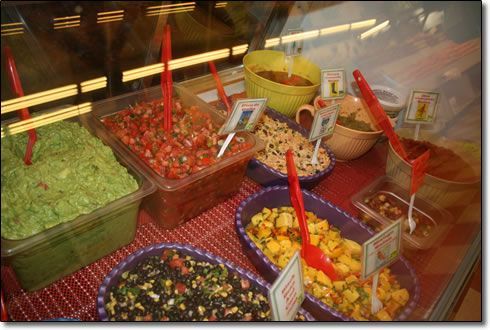 A display case filled with a variety of salsas and guacamole