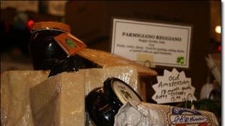A jar of parmigiano reggiano cheese sits next to a jar of old amsterdam cheese