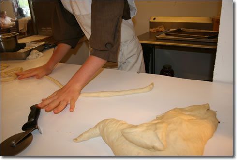 A person is cutting a piece of dough on a table