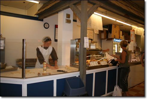 A woman is standing at a counter in a bakery