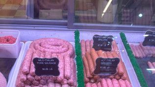 There are many different types of sausages on display in a butcher shop.