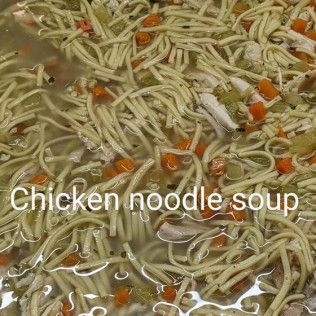 A pot of chicken noodle soup with carrots and celery.