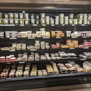 A refrigerator filled with lots of food in a grocery store.