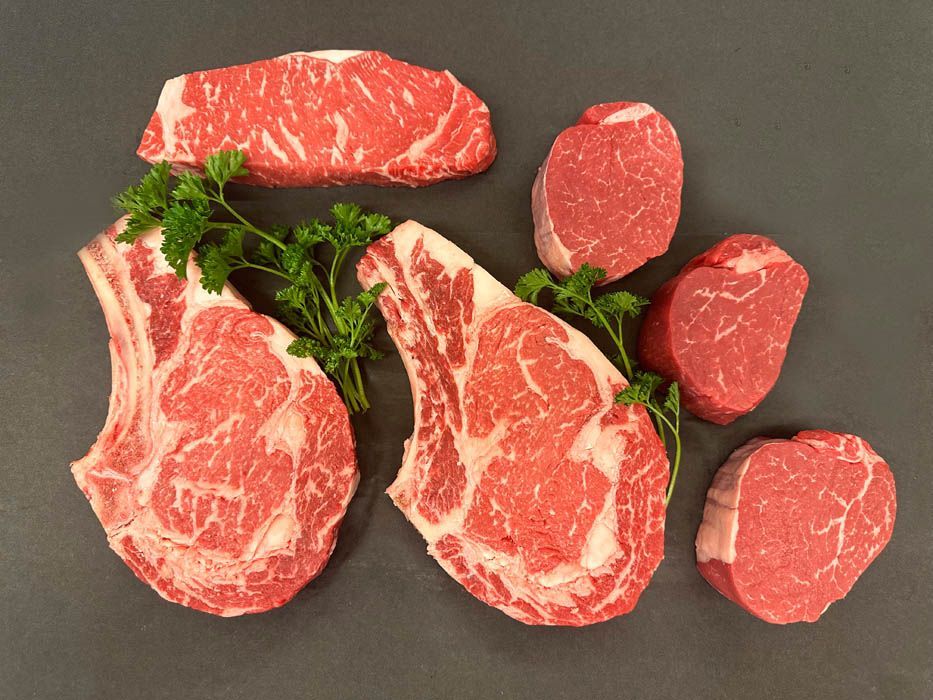 A variety of raw steaks are laid out on a table