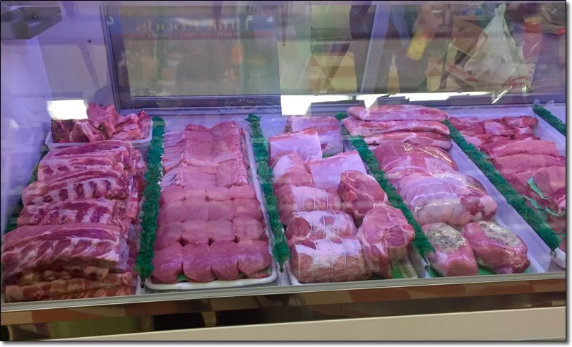 A variety of meats are displayed in a butcher shop.