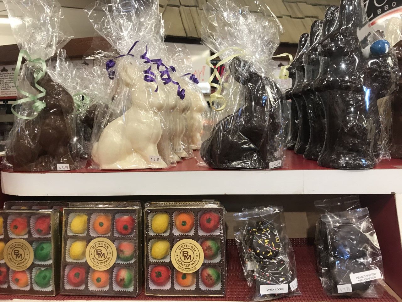 A shelf filled with chocolate bunny figurines and boxes of fruit.