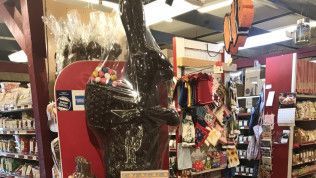 A large chocolate bunny is sitting in the middle of a store.