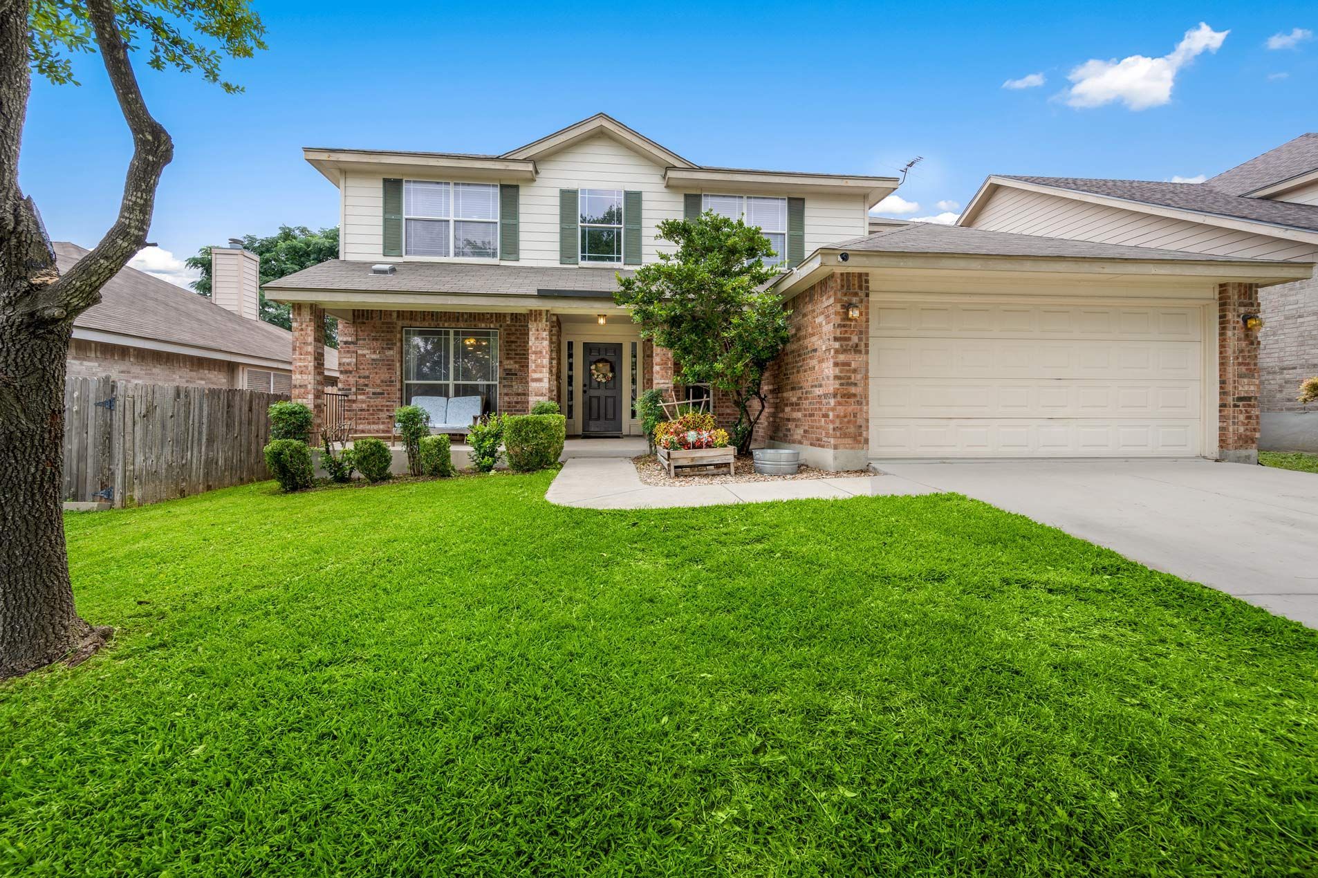Two-story home with brick and siding, green lawn, and a two-car garage under a blue sky.