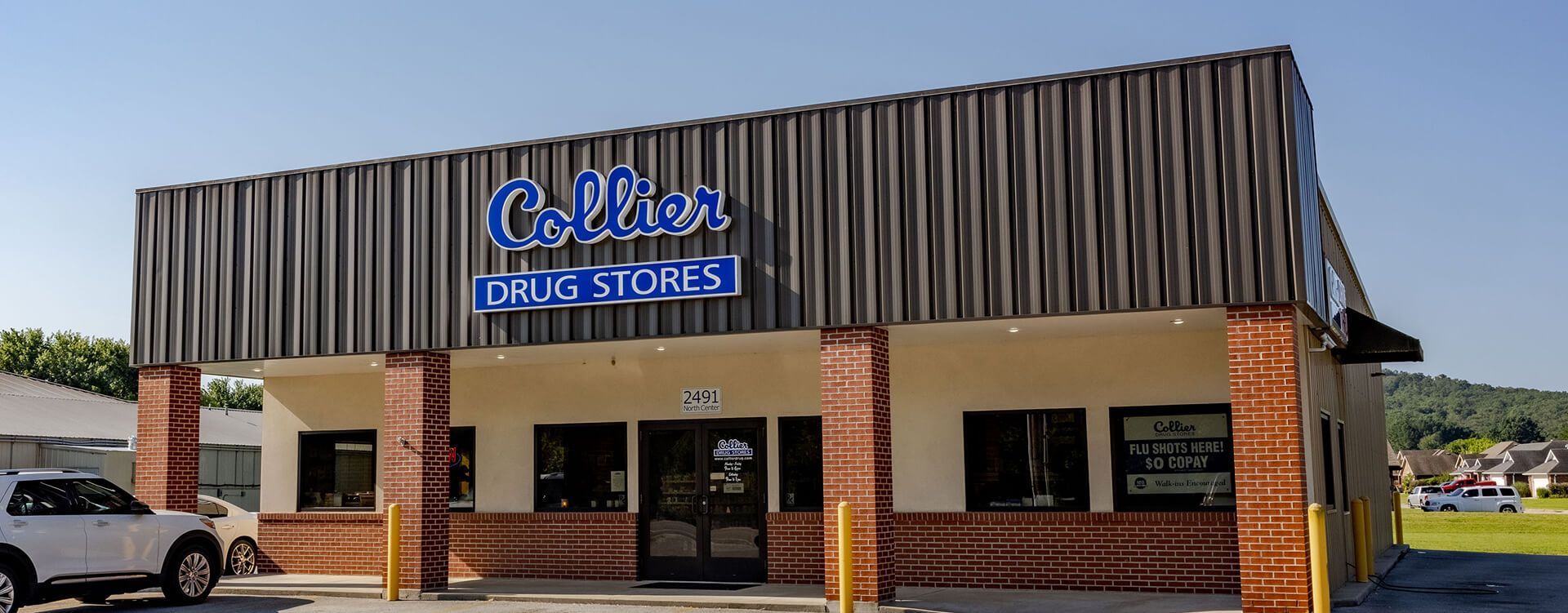 A white car is parked in front of a large building.