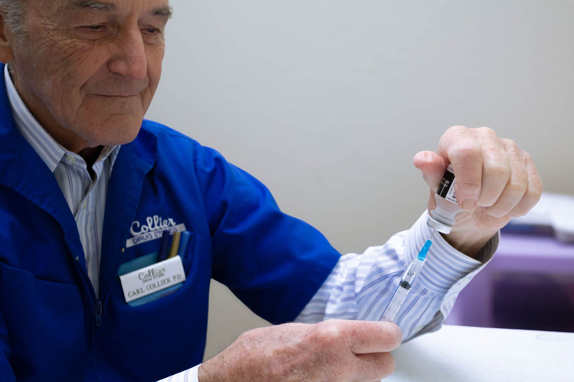 A person wearing blue gloves is holding a syringe.