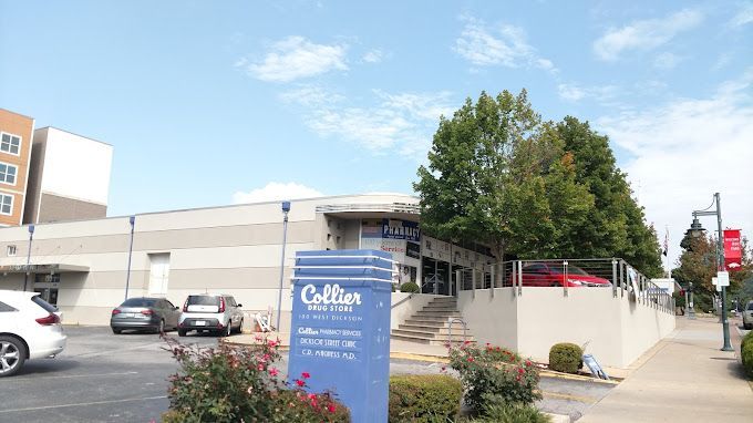 A blue sign in front of a building with cars parked in front of it.