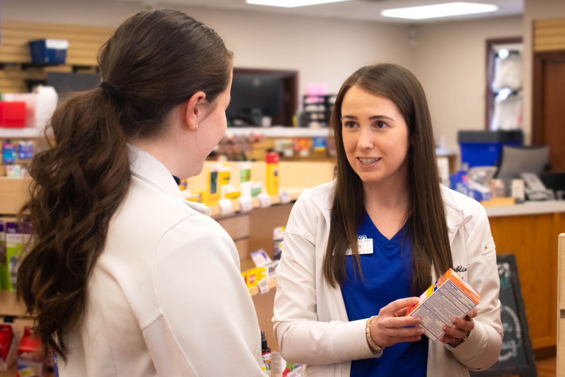 A female pharmacist is giving a prescription to a man in a pharmacy.