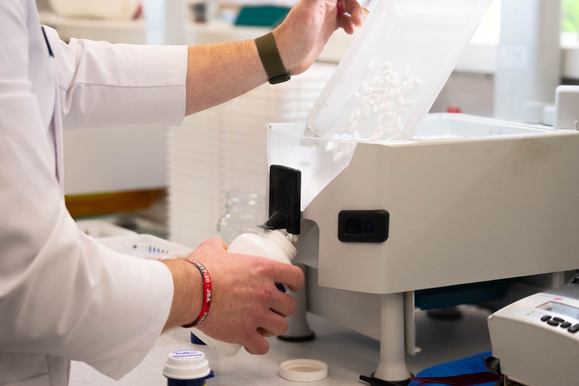 A person wearing blue gloves is holding a swab and a test tube.