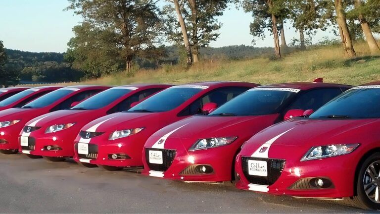 A row of red cars are parked next to each other
