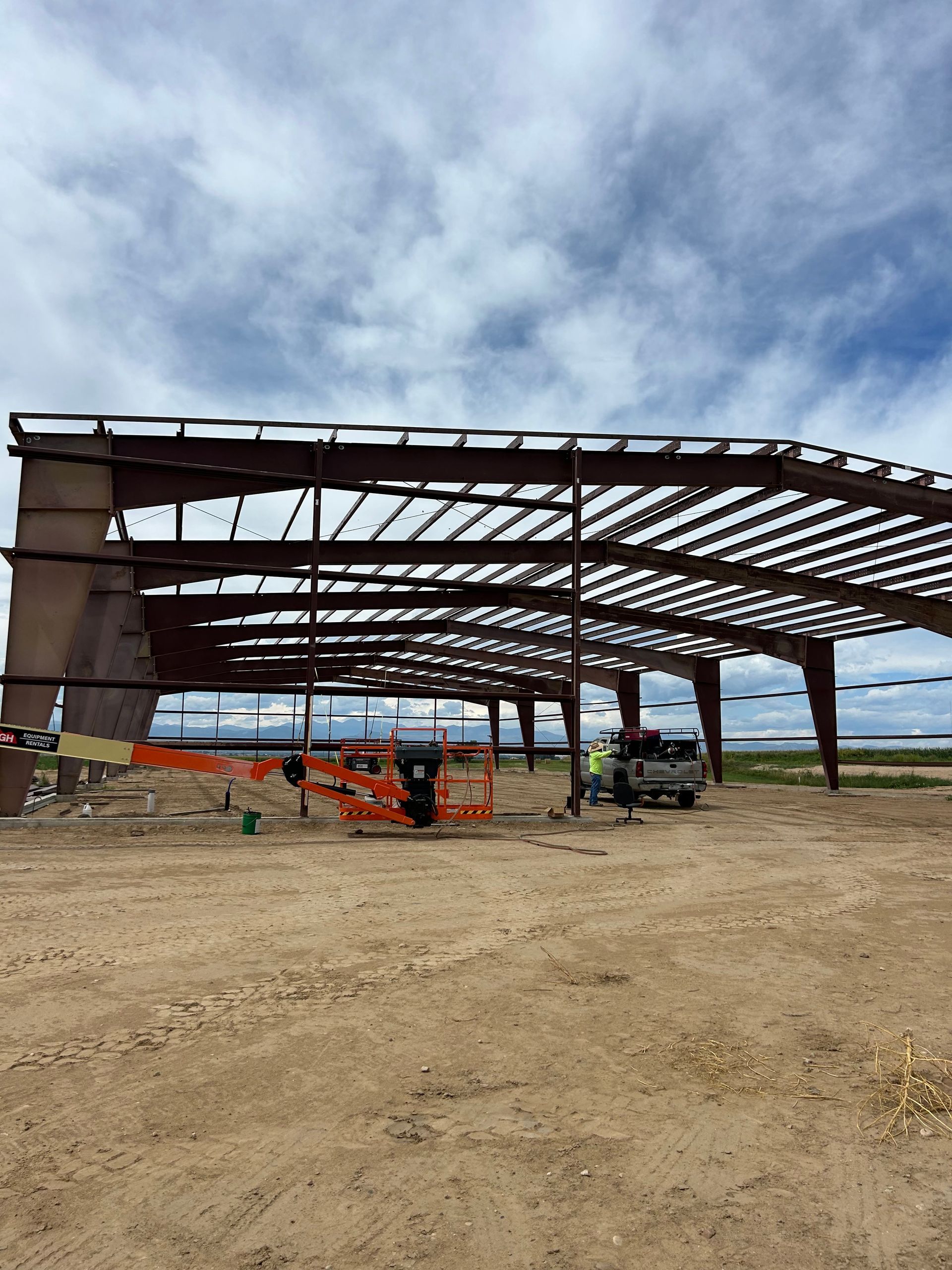 A large metal structure is being built in a dirt field.