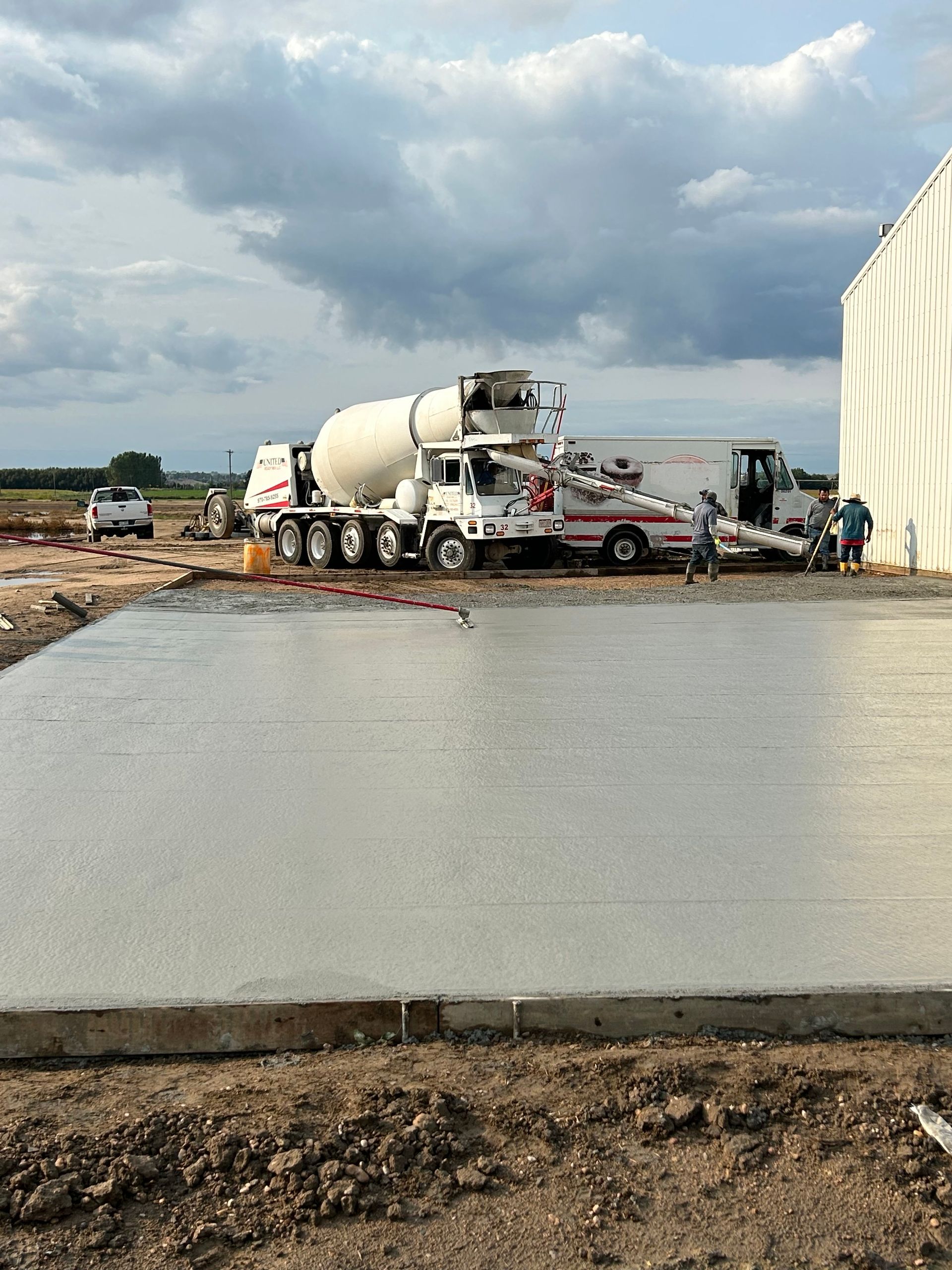 A concrete floor is being poured in front of a building.