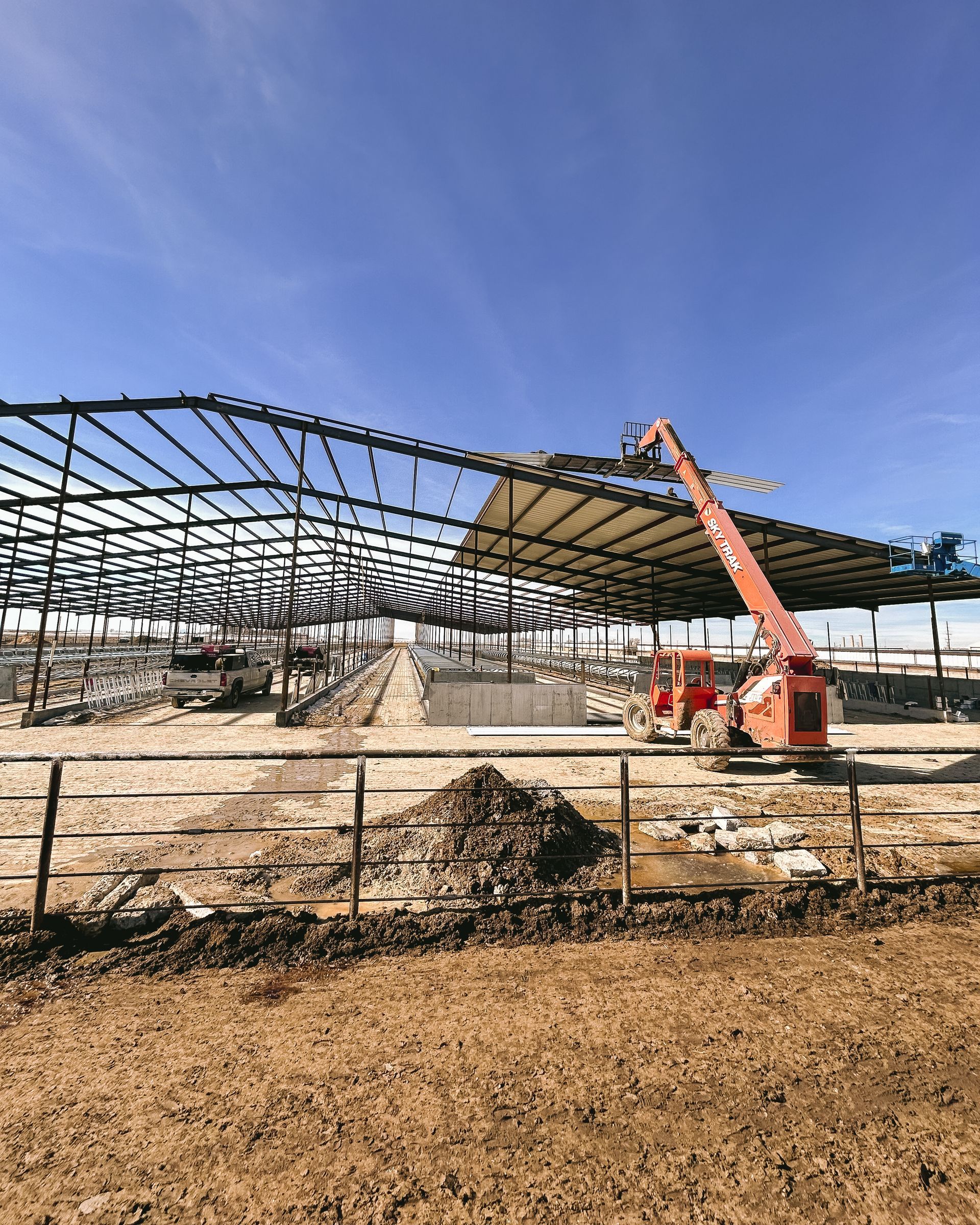 A large metal structure is being built on top of a dirt field.