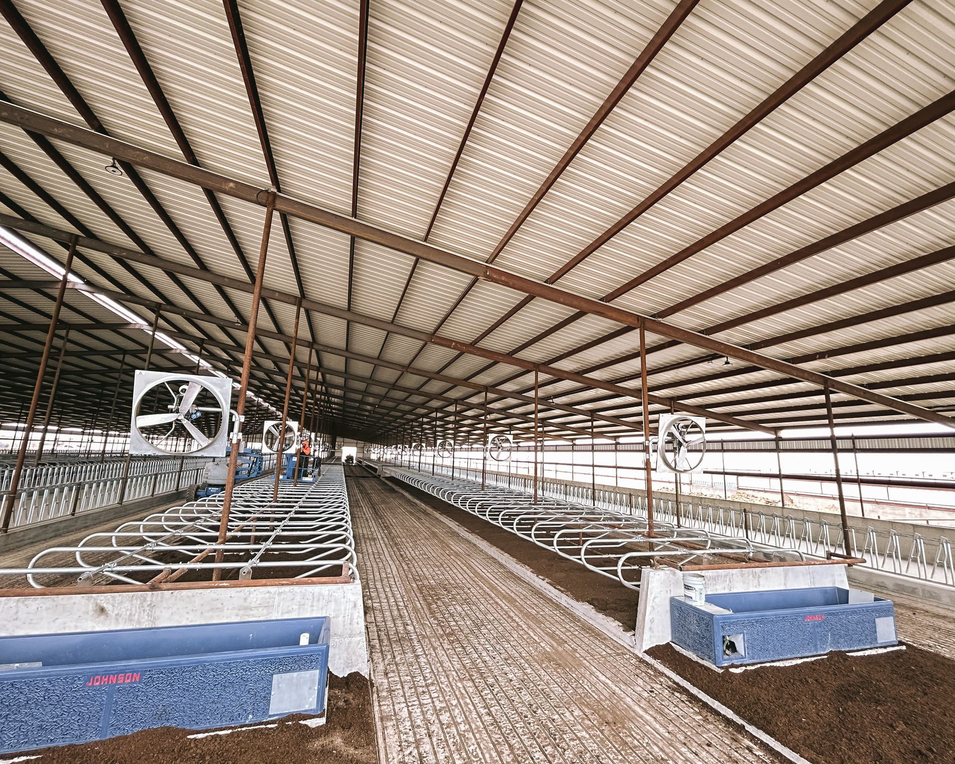 There are a lot of fans hanging from the ceiling of a barn.