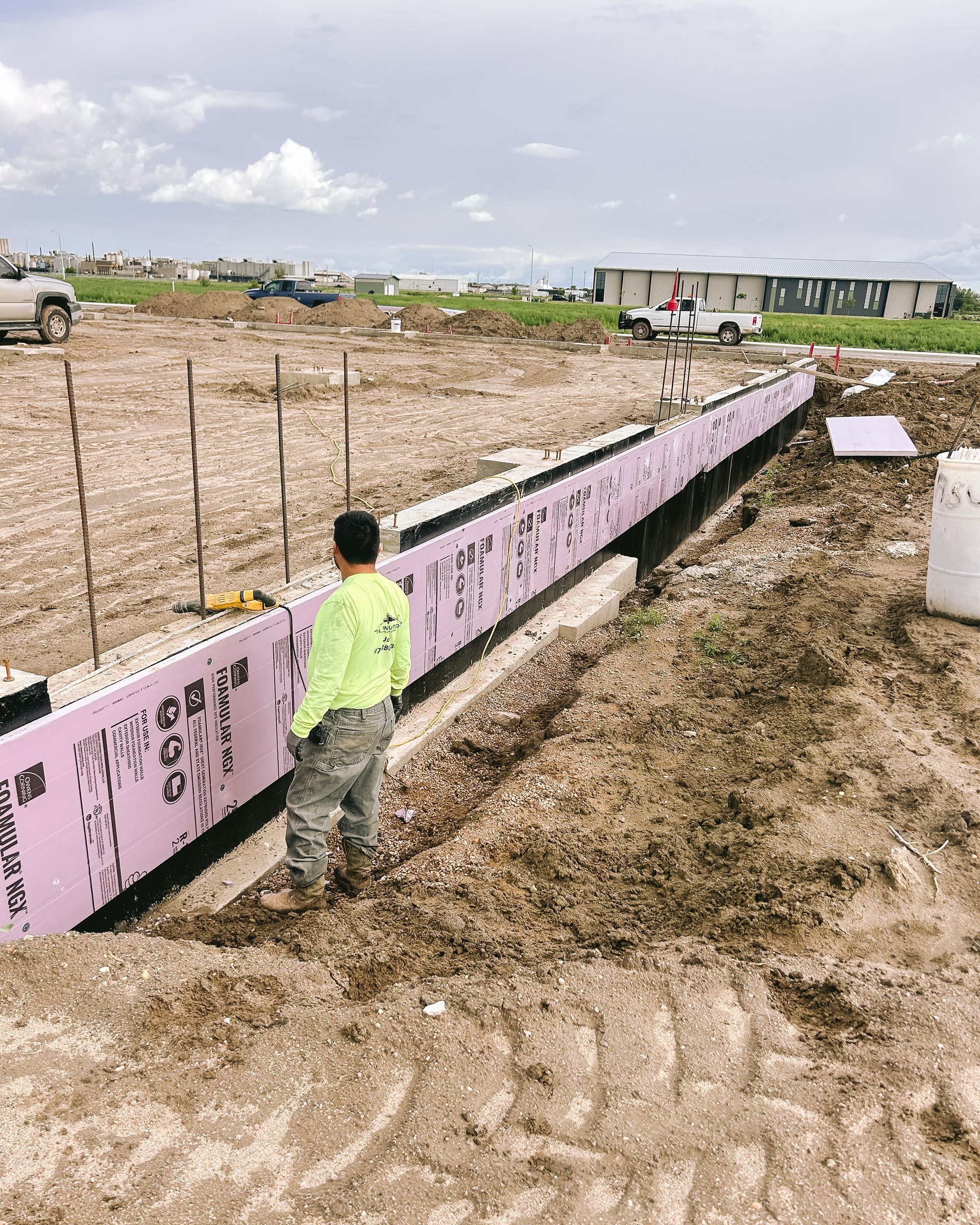 A man is standing in the dirt next to a pink wall.