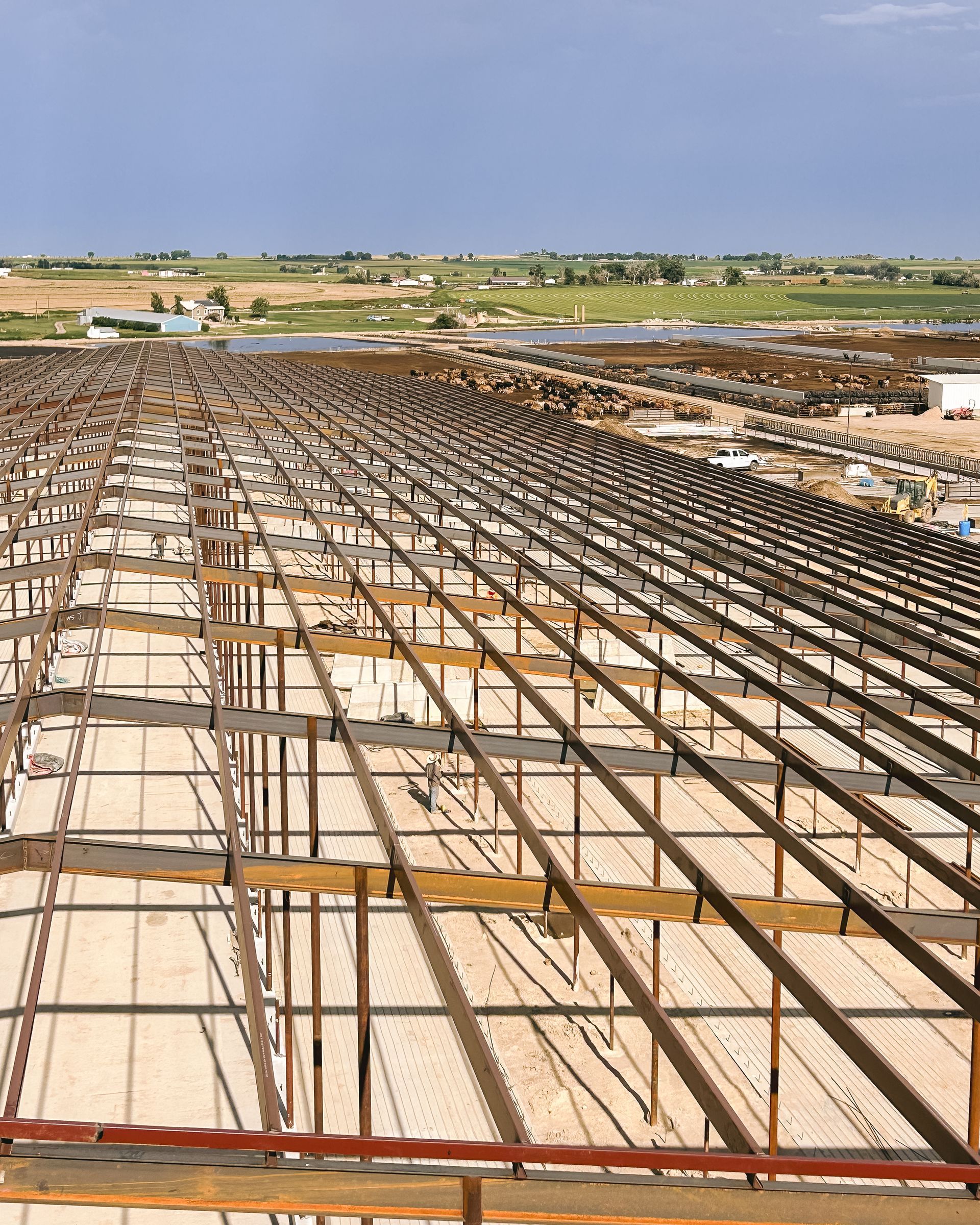 A large metal structure is being built on top of a dirt field.