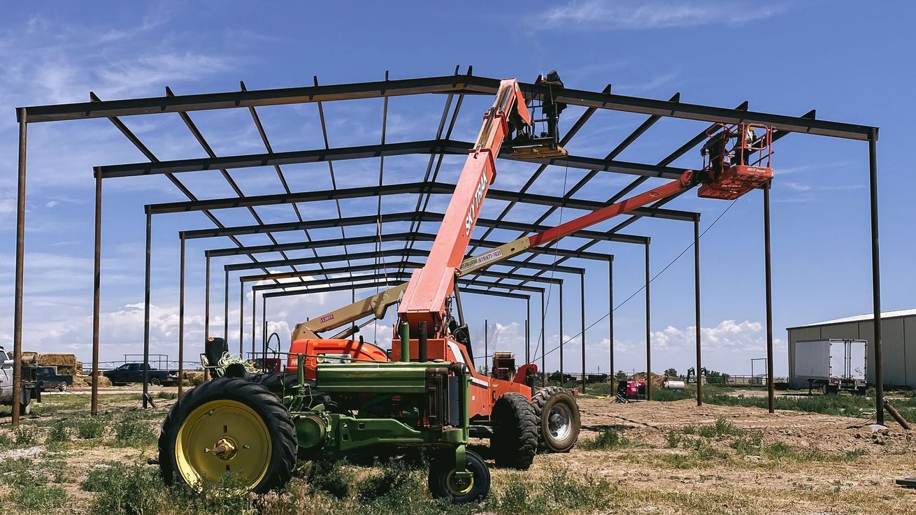 A tractor is parked in front of a building under construction.