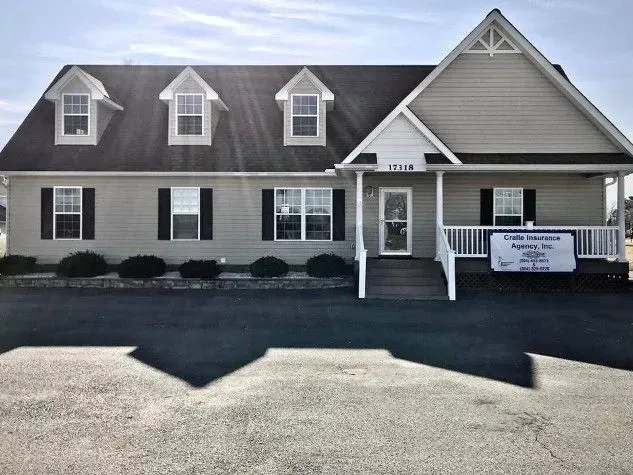 Sandy path through beach grass leads to the ocean under a pale blue sky.