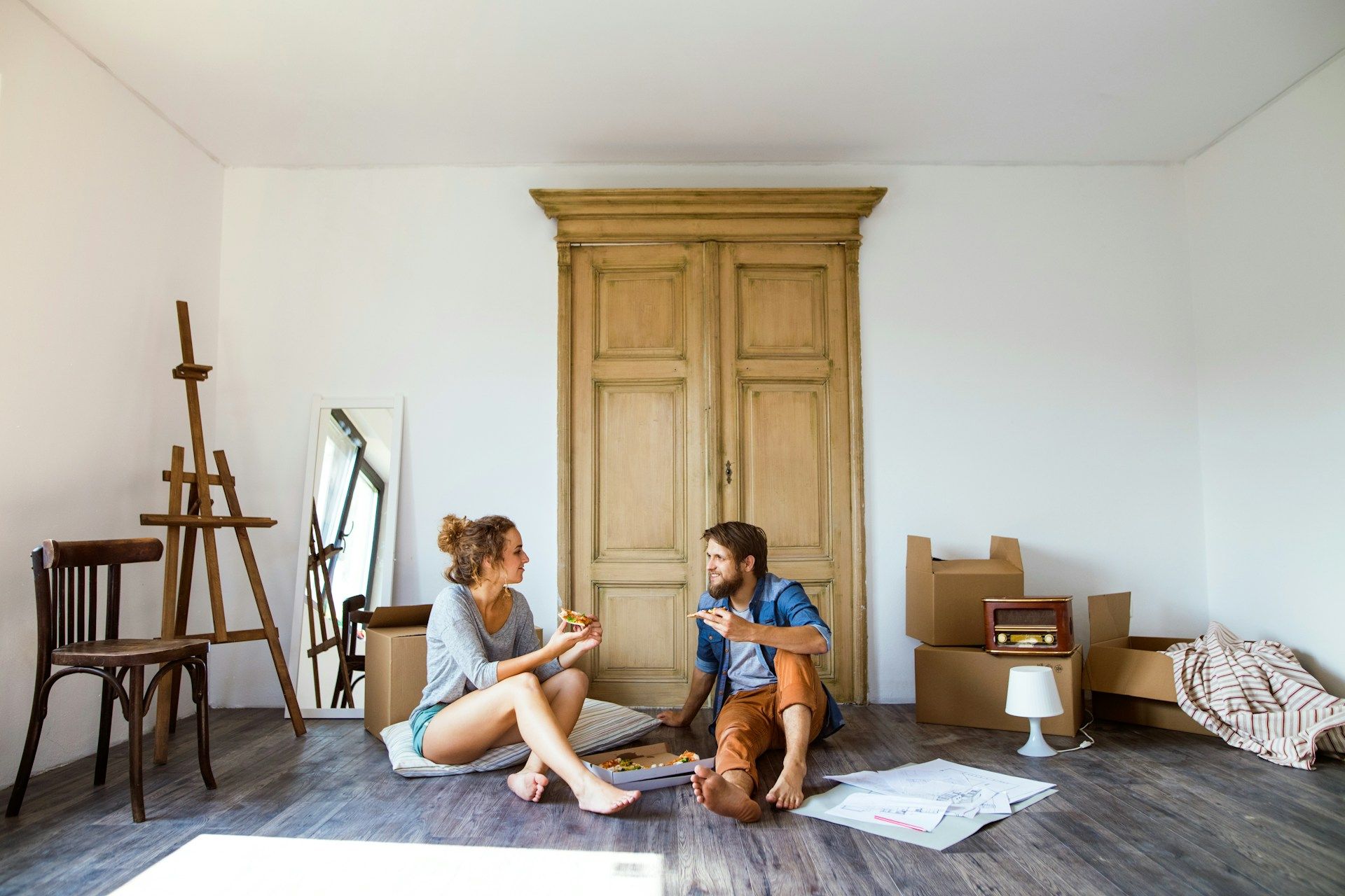 Man in gray hoodie consoles woman in white shirt on a couch.