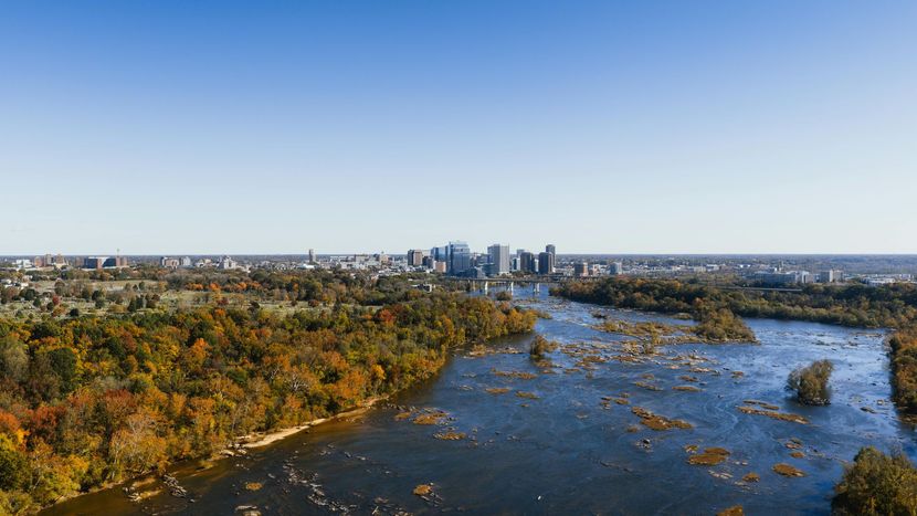 Sandy path through beach grass leads to the ocean under a pale blue sky.