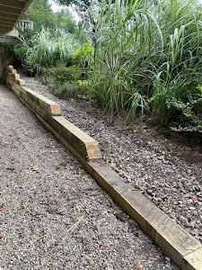 A wooden fence along a gravel path in a garden.