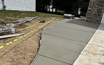A concrete walkway is being built in front of a house.