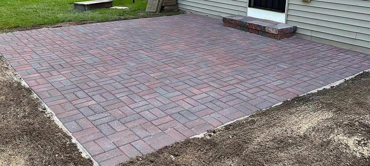 A brick patio is being built in front of a house.
