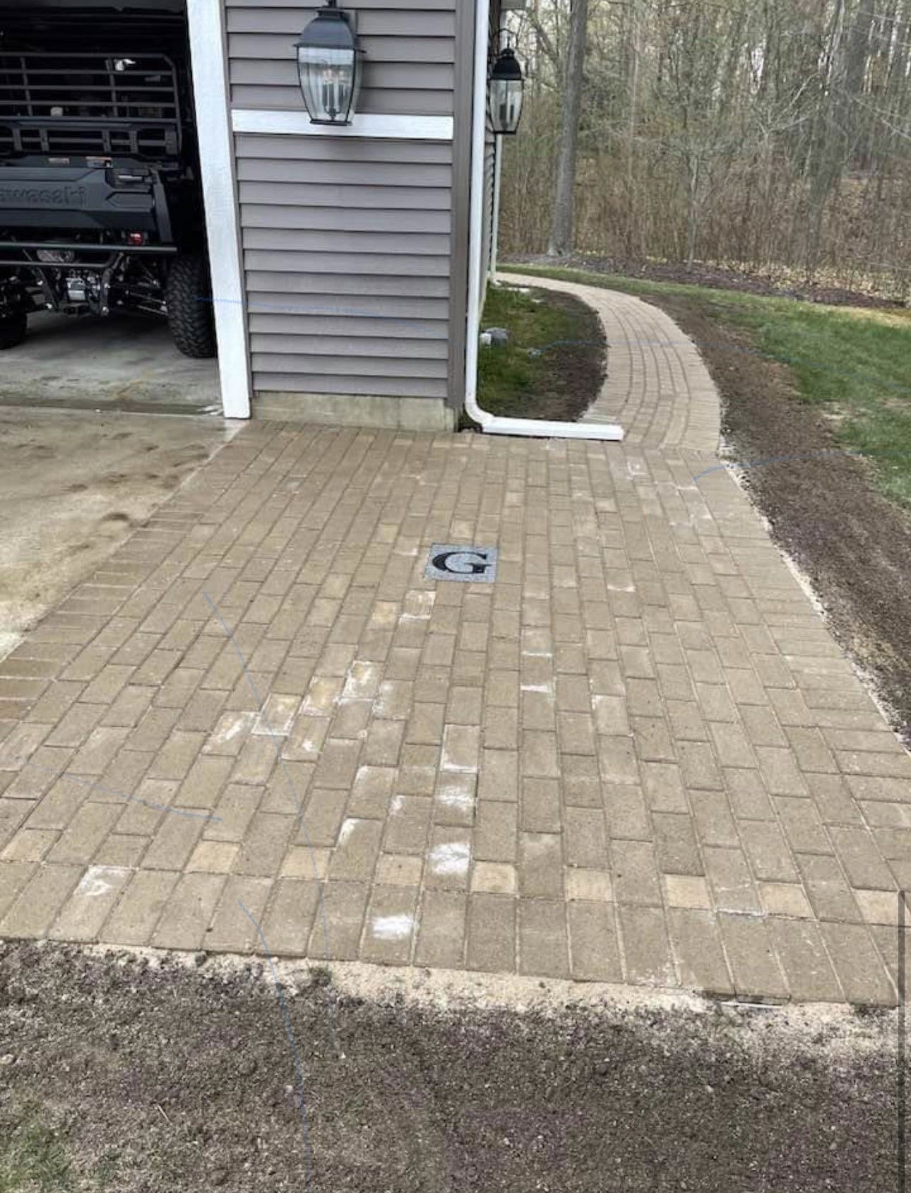 A brick walkway leading to a garage next to a house.