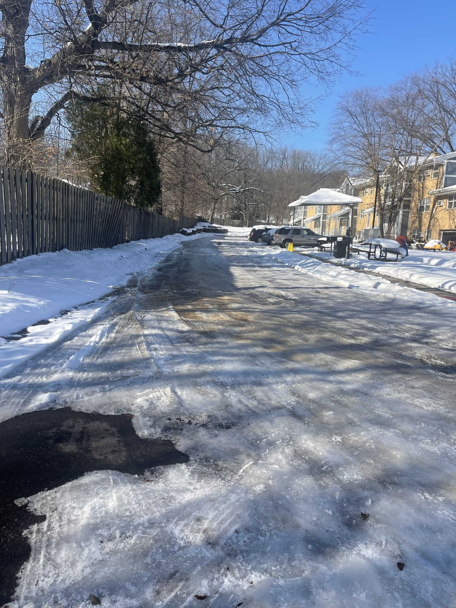 A snowy street with cars parked on the side of it
