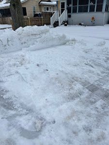 There is a lot of snow on the ground in front of a house.