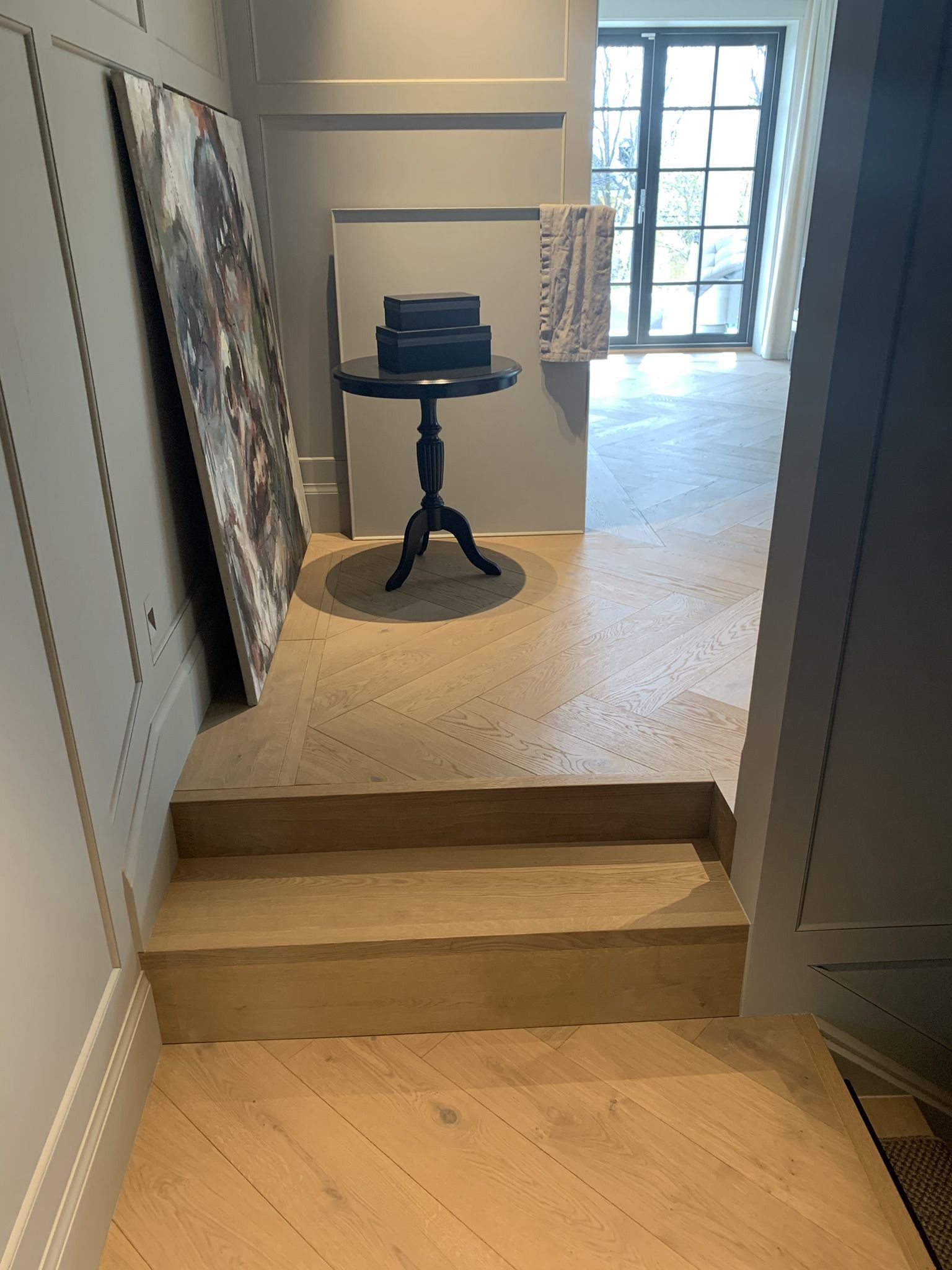 Et tregulv med trapp og bord i en gang.