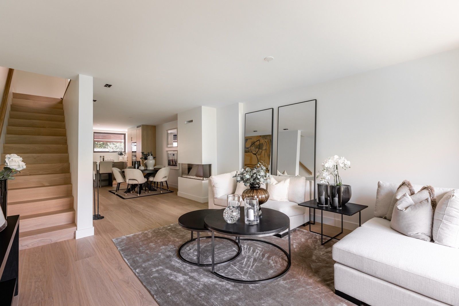 En stue fylt med møbler og en trapp som fører til spisestuen.