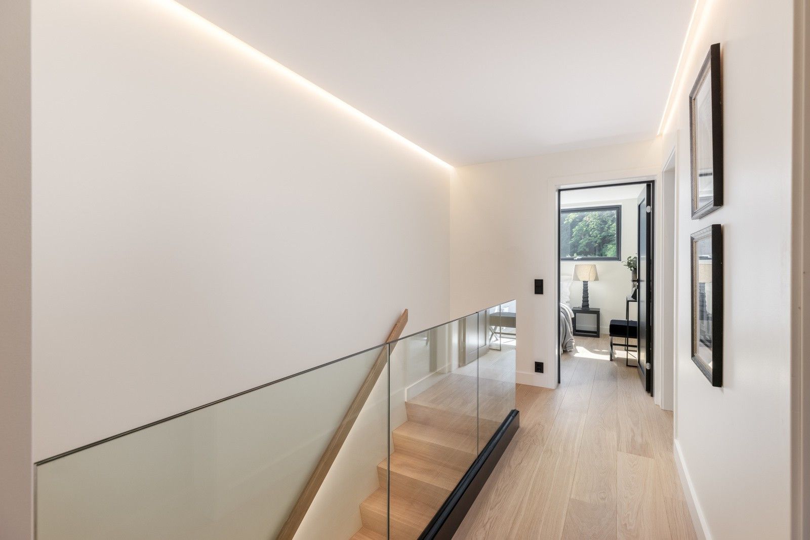 En gang med trapp og glassrekkverk i et hus.