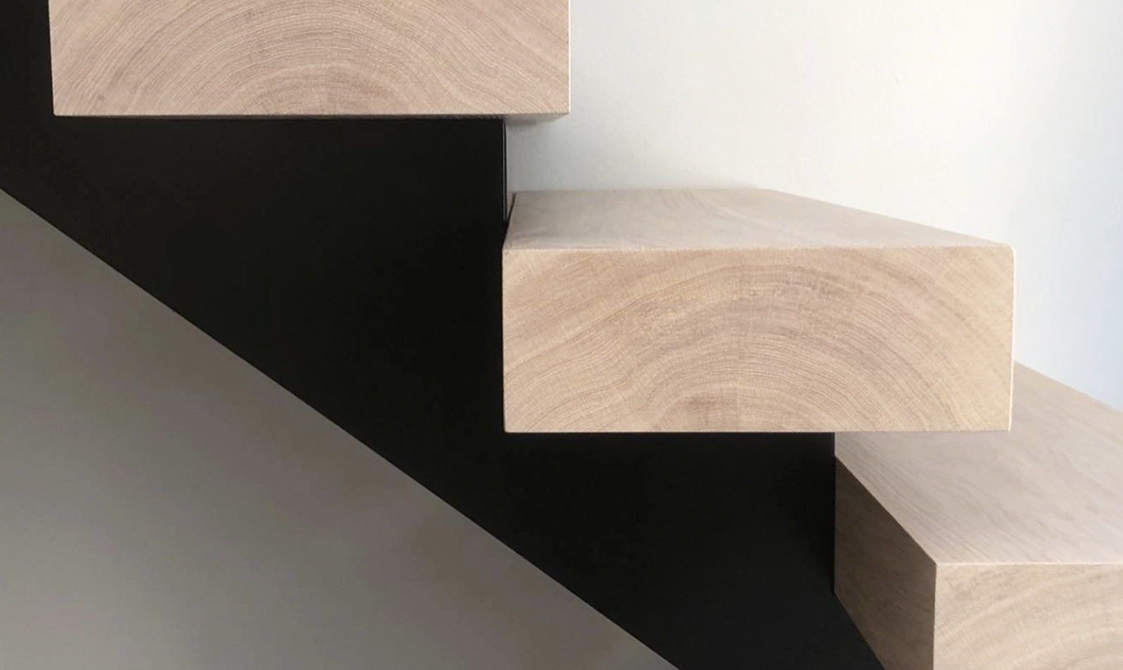 Et nærbilde av en tretrapp med svart rekkverk.