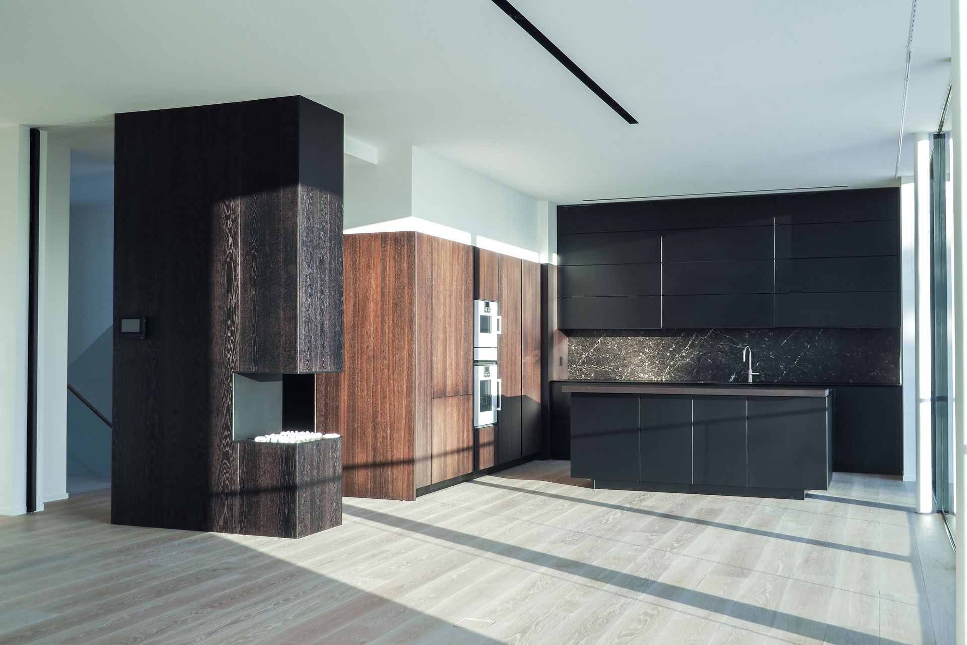 Et kjøkken med sorte skap og tregulv