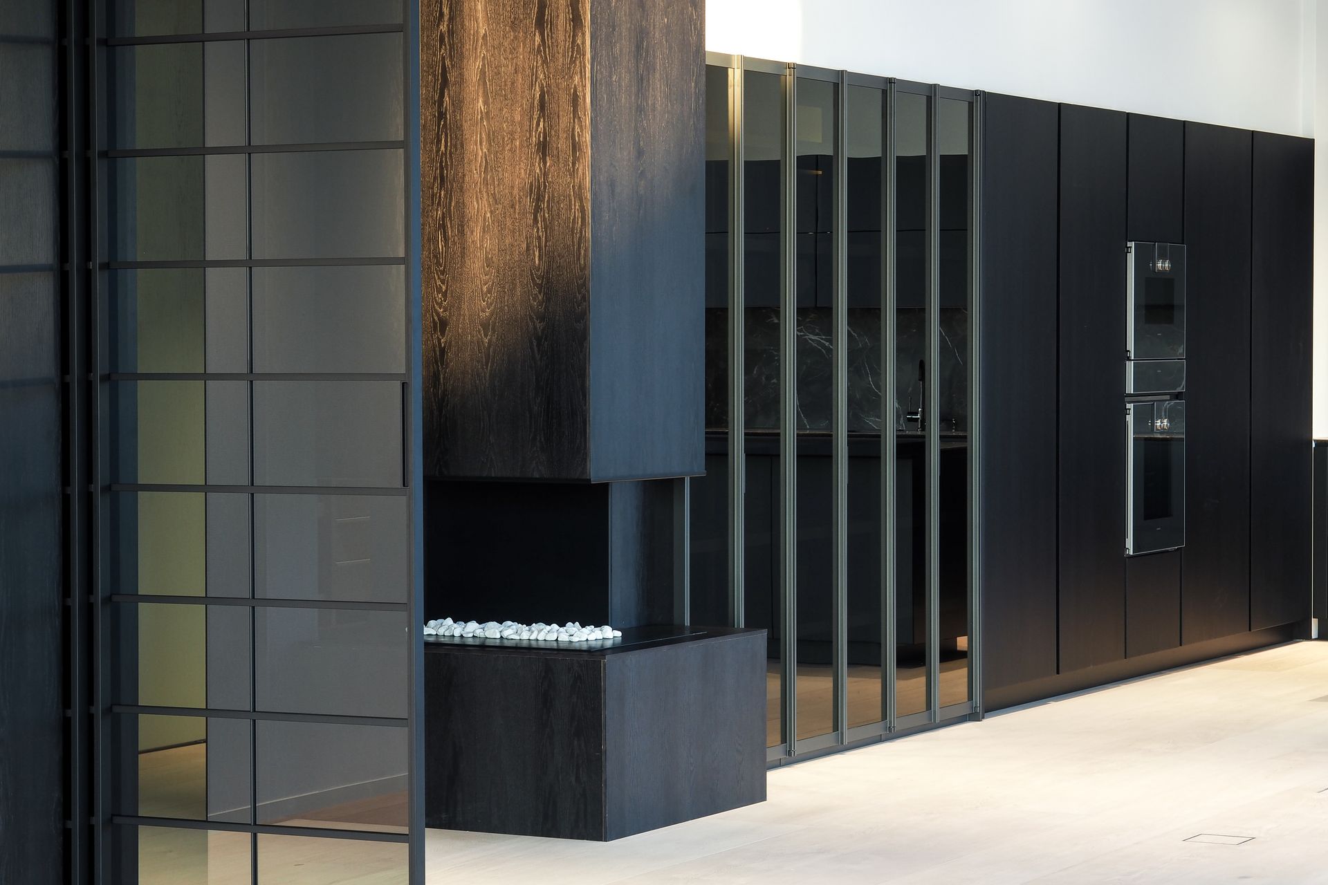 Et kjøkken med sorte skap og skyvedører i glass