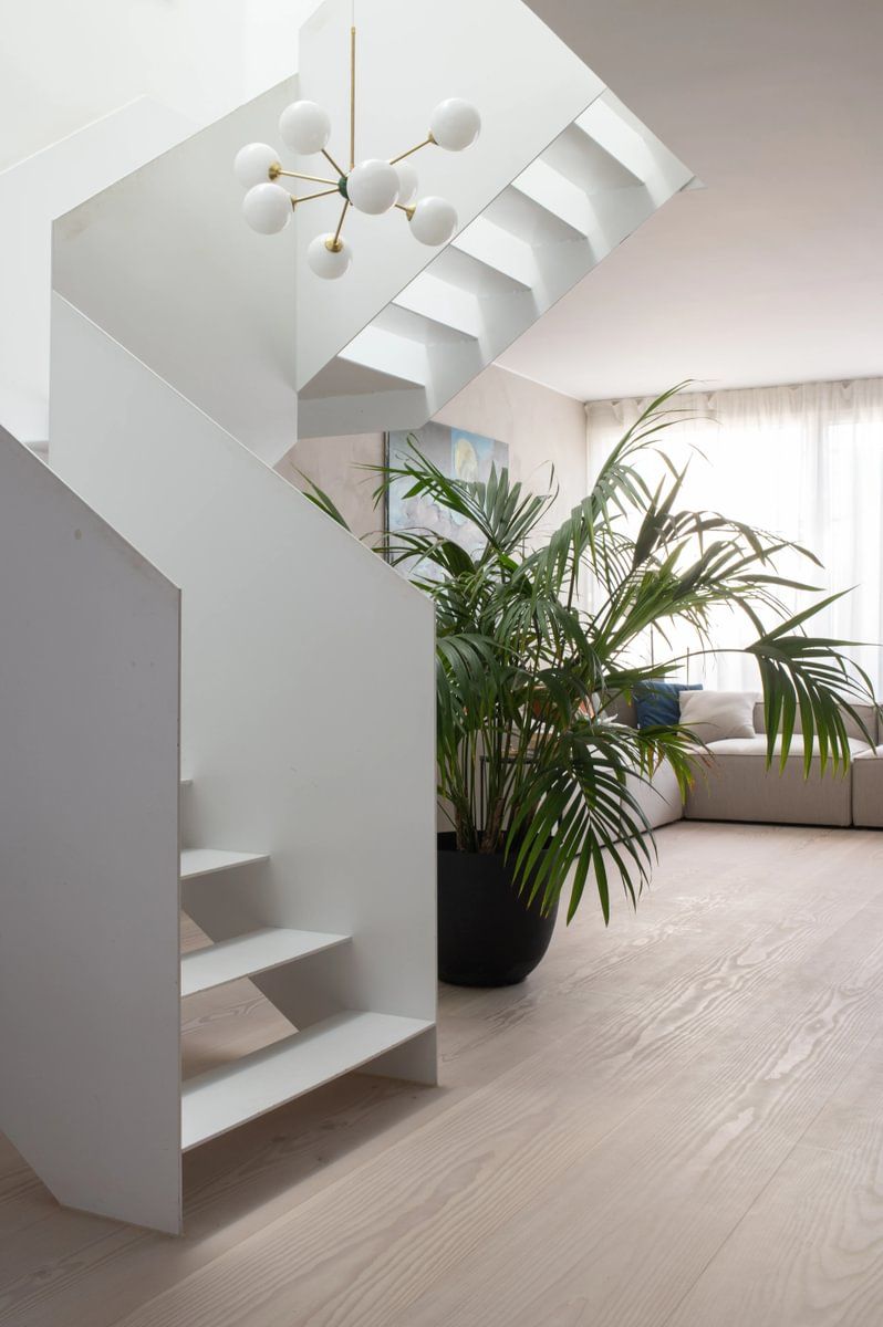 En hvit trapp i en stue ved siden av en potteplante.