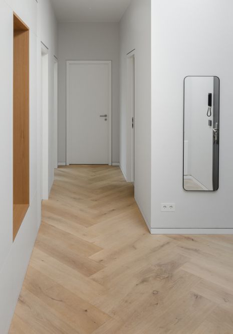 En gang med tregulv og speil på veggen