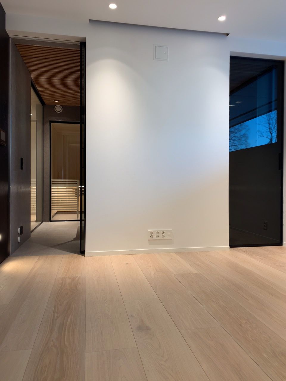 Et tomt rom med tregulv og hvite vegger