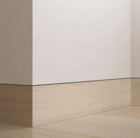 Et rom med hvit vegg og tregulv.