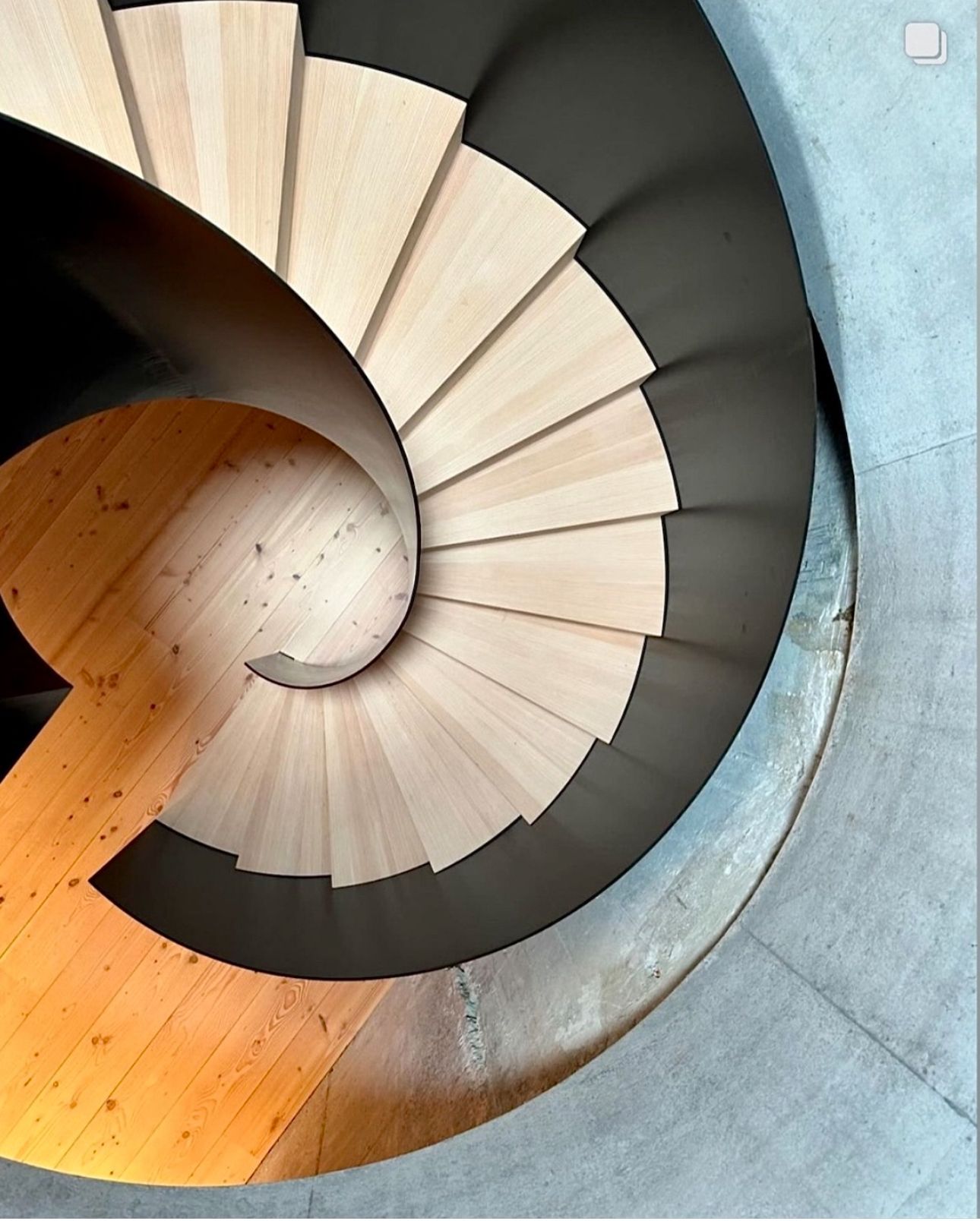 En spiraltrapp med tretrinn og svart rekkverk